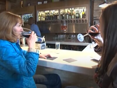 Две женщины пьют вино за барной стойкой
