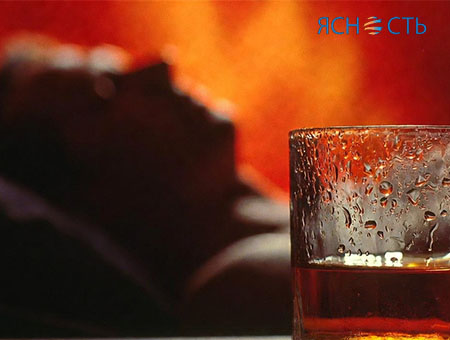 Изображение в красных оттенках: мужчина лежит в кровати и рядом стакан алкоголя